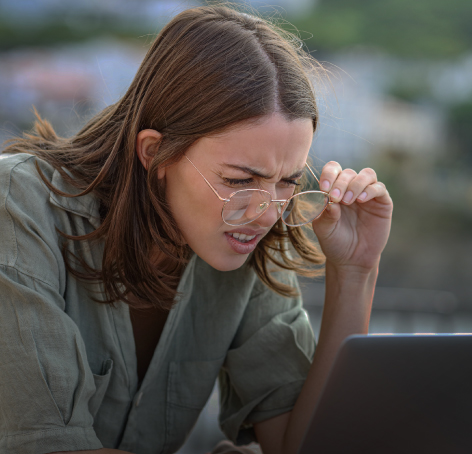 mujer esforzandose por ver bien pantalla de portatil