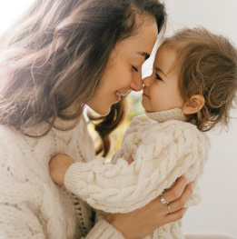 mama cargando feliz a su bebe de 18 meses