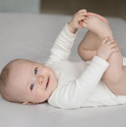 bebe de 6 meses acostado y tocando sus pies