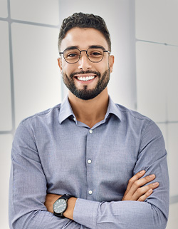 hombre de gafas sonriendo con los brazos cruzados