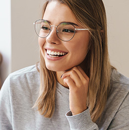 mujer con gafas luciendo sus implantes dentales
